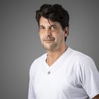 Reinhard Kofler Ritratto di un uomo con maglietta bianca e ciondolo su sfondo grigio