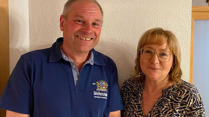 Petra Holzer als Bezirksobfrau bestätigt Lächelnder Mann in blauem Hemd und Frau mit Brille vor weißer Wand