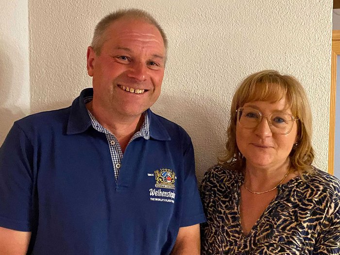 Petra Holzer als Bezirksobfrau bestätigt Lächelnder Mann in blauem Hemd und Frau mit Brille vor weißer Wand