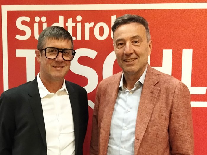 I falegnami puntano su scambio, innovazione e qualità Due uomini sorridenti davanti a uno sfondo rosso con scritta Südtirol