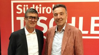 News Zwei lächelnde Männer vor rotem Hintergrund mit Aufschrift Südtirol