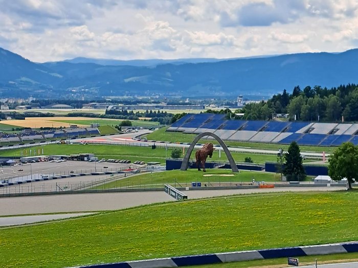 Kulturreise ins Burgenland – Oper und Musical als Programmschwerpunkt Rennstrecke in hügeliger Landschaft mit großer Bison-Statue und bewölktem Himmel