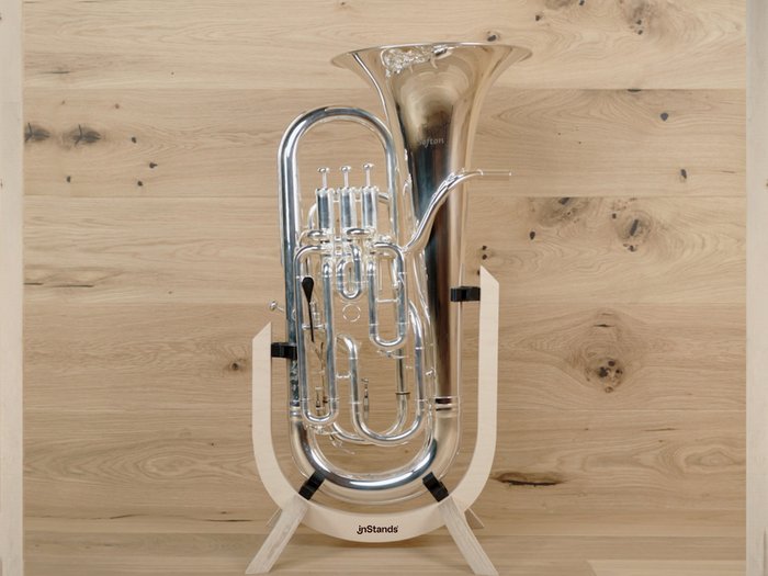 Gleich drei Auszeichnungen in Platin Silbernes Blasinstrument auf einem Holzständer vor Holzwand