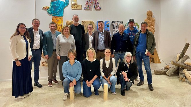 Home Eine Gruppe posiert in einem Ausstellungsraum vor verschiedenen Kunstwerken