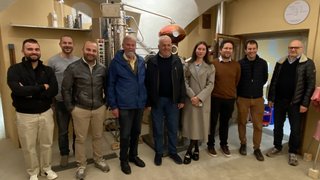 News Gruppe von zehn Personen steht in einem Raum mit Destillationsanlage im Hintergrund