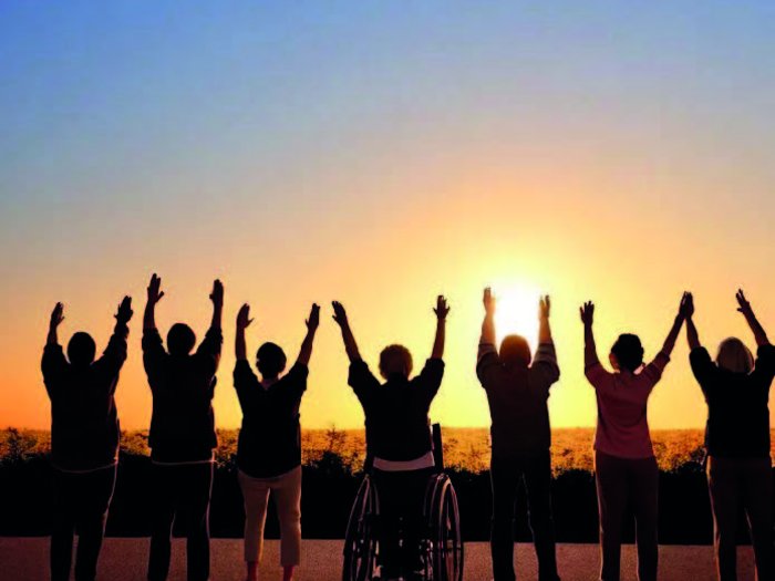 Einladung zur Tagung: „Wir haben’s geschafft!“ Inklusion in der Arbeitswelt Menschen, darunter eine im Rollstuhl, heben bei Sonnenuntergang die Arme hoch