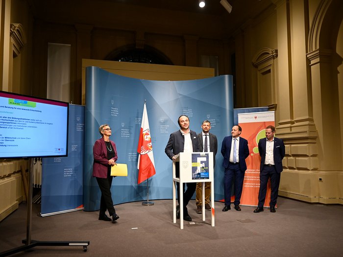 Futurum und World Skills Italy von 28. bis 30. September in Bozen Fünf Personen bei einer Pressekonferenz in einem Saal mit Flagge und Monitor
