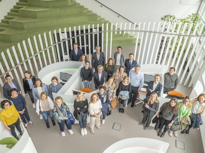 La delegazione altoatesina ha visitato il Talentcenter di Graz Foto di gruppo di 27 persone in ufficio moderno con gradini verdi e divisori bianchi