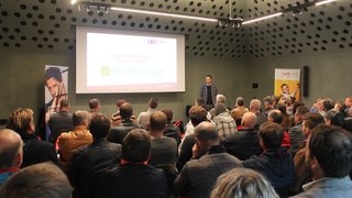 © lvh.apa Mann hält Vortrag vor Publikum in modernem Konferenzraum