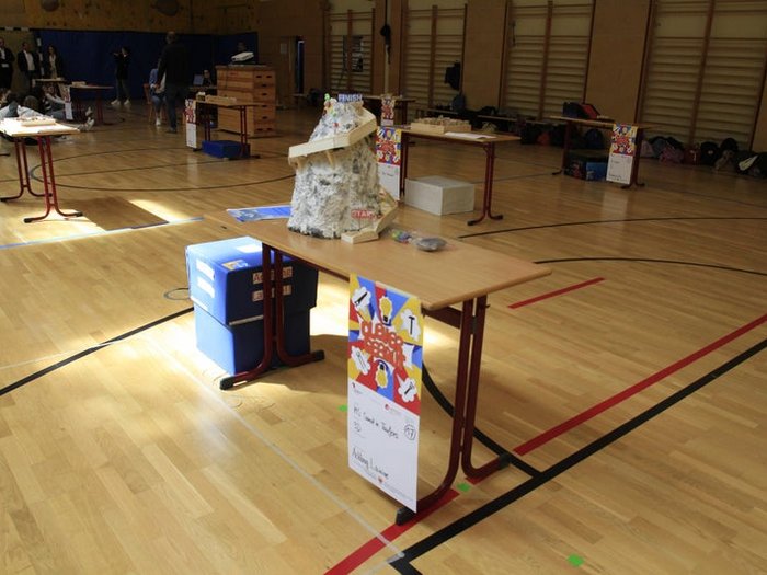 Kreative Spielideen: Preisverleihung für "Clever gebaut" Modell auf Tisch in Turnhalle mit Personen im Hintergrund