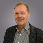 Das lvh-Team Porträt eines lächelnden Mannes mit hellem Haar vor grauem Hintergrund