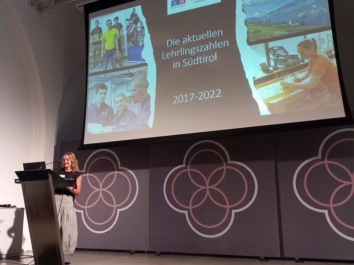 Europäisches Kammertreffen Frau präsentiert Lehrlingszahlen in Südtirol von 2017 bis 2022 auf einer Bühne.