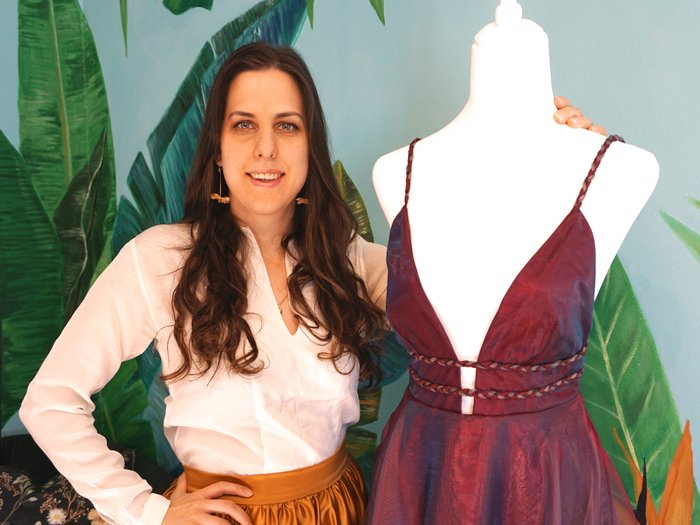 Handwerk ist weiblich – und selbstbewusst Frau neben Schaufensterpuppe mit rotem Kleid vor Wand mit Pflanzenmuster