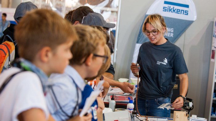 WorldSkills Italy: Junge Talente im Wettkampf Frau erklärt Kindern ein technisches Gerät auf einer Messe