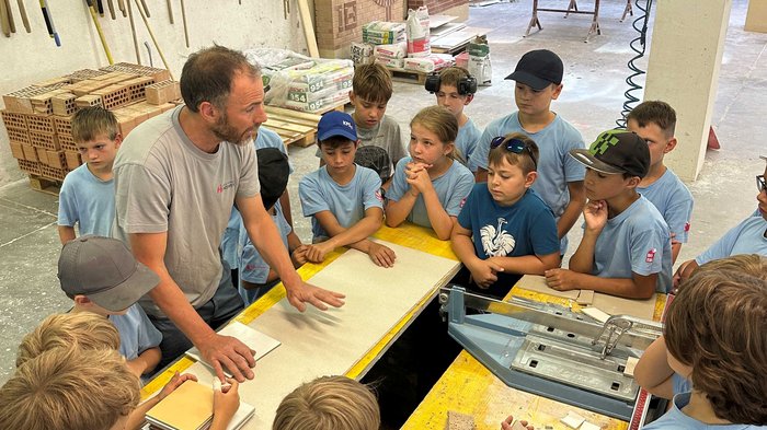 Kids-Academy 2024: Eine lehrreiche Erfahrung im Vinschgau Lehrer erklärt Kindern Handwerksarbeit in Werkstatt