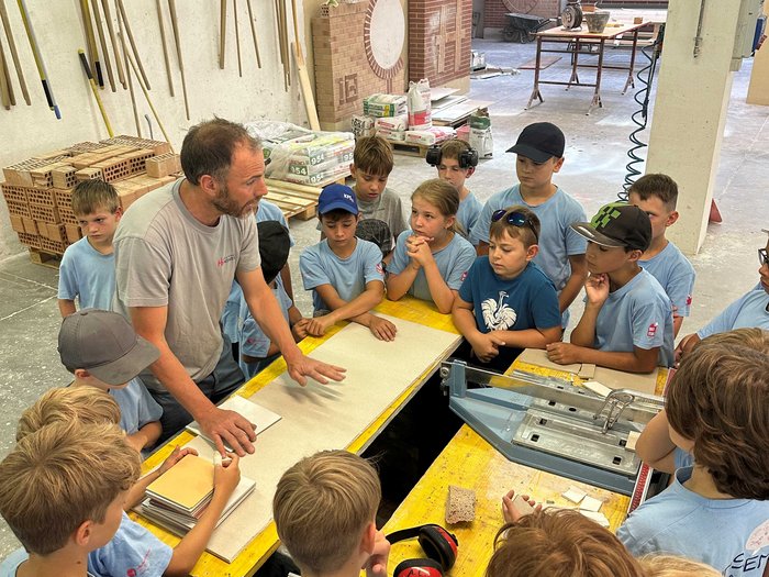 Kids-Academy 2024: Eine lehrreiche Erfahrung im Vinschgau Lehrer erklärt Kindern Handwerksarbeit in Werkstatt