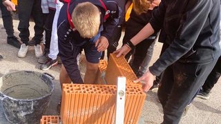 News Jugendliche mauern mit Ziegelsteinen und verwenden Wasserwaage