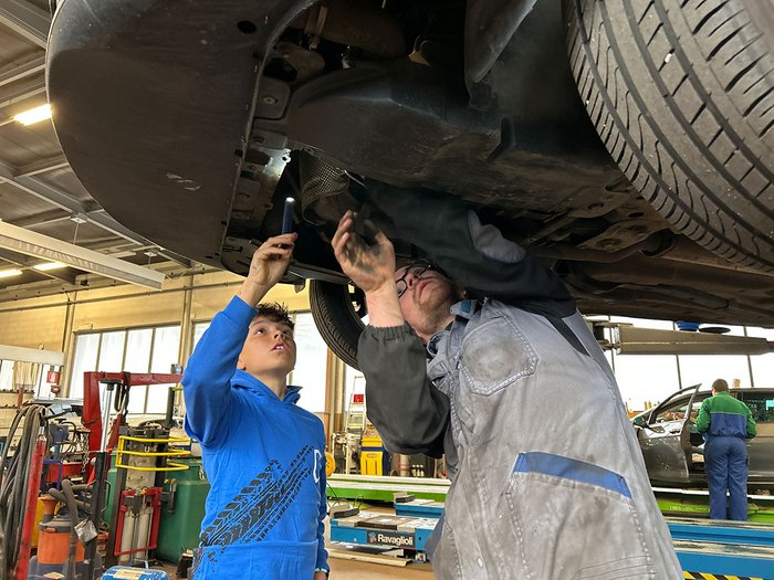 Handwerk hautnah erleben: Die Sarner Mittelschüler/innen entdecken ihre berufliche Zukunft Mann und Junge reparieren ein Auto in der Werkstatt unter dem Fahrzeug