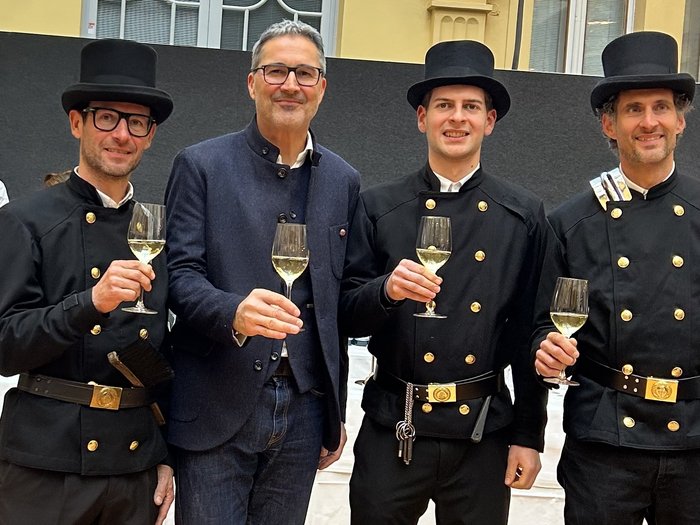 Wo ein Gruß mehr ist als ein Ritual. Vier Männer, drei in Schornsteinfeger-Uniform, stoßen mit Weingläsern an