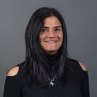 Frauen im Handwerk Porträt einer lächelnden Frau mit schwarzem Pullover und Halskette vor grauem Hintergrund