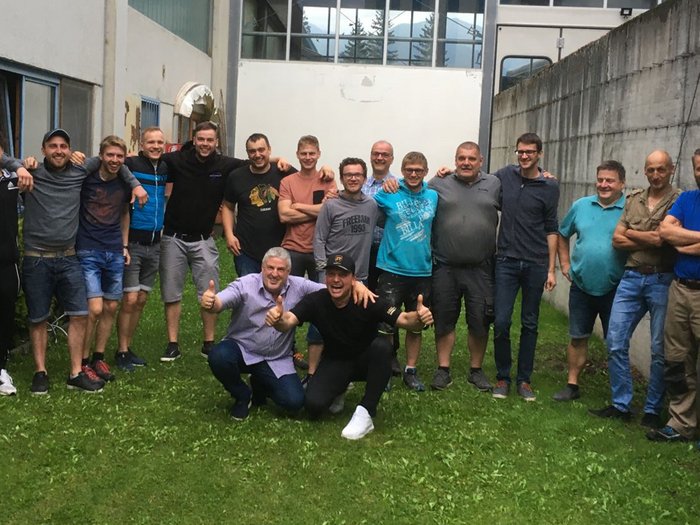 Bodenleger: Eine gesellige Runde mit vielen Gesprächsthemen Gruppe von 17 Männern steht im Hof zwischen Gebäuden auf Gras