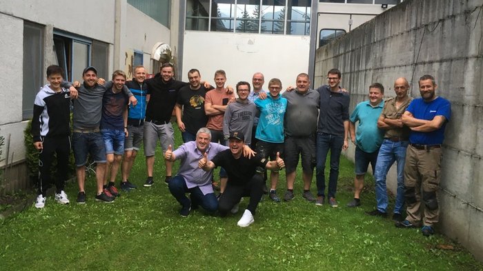 Bodenleger: Eine gesellige Runde mit vielen Gesprächsthemen Gruppe von 17 Männern steht im Hof zwischen Gebäuden auf Gras