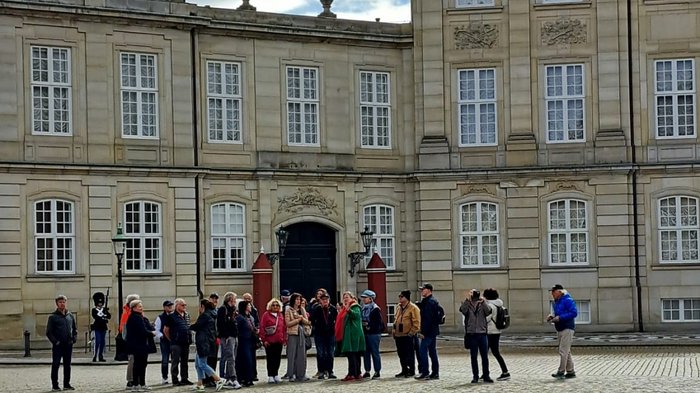 Reisefreudige Althandwerker/innen Gruppe von Touristen vor historischem Gebäude mit steinernem Hof bei bewölktem Himmel