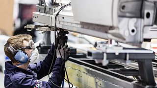 News Arbeiter mit Schutzbrille und Maske bei Schweißarbeiten an Metallrahmen