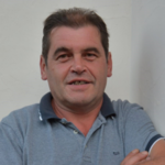 Burggrafenamt Mann mittleren Alters mit grauem Poloshirt vor weißer Wand