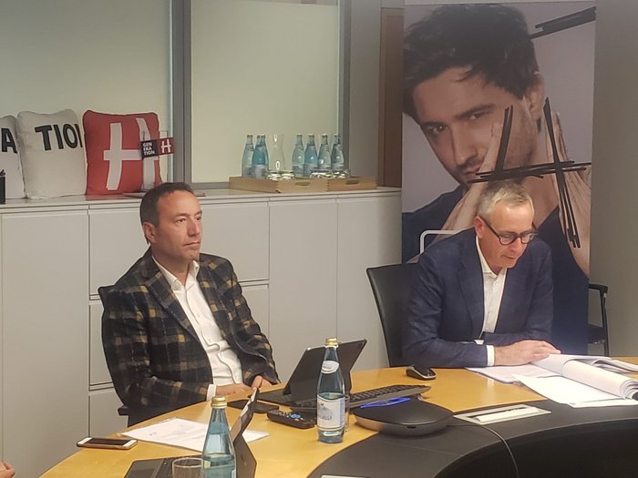 Webinar Dienstwohnung & Mitarbeiterunterkünfte Zwei Männer in Anzügen sitzen bei Besprechung an einem Konferenztisch mit Dokumenten