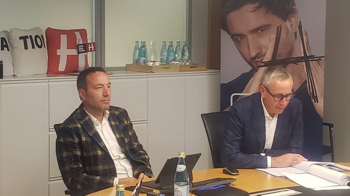 Webinar alloggio di servizio e alloggio temporaneo di personale in zone produttive Due uomini in giacca seduti a un tavolo di conferenza con documenti e bottiglie d'acqua