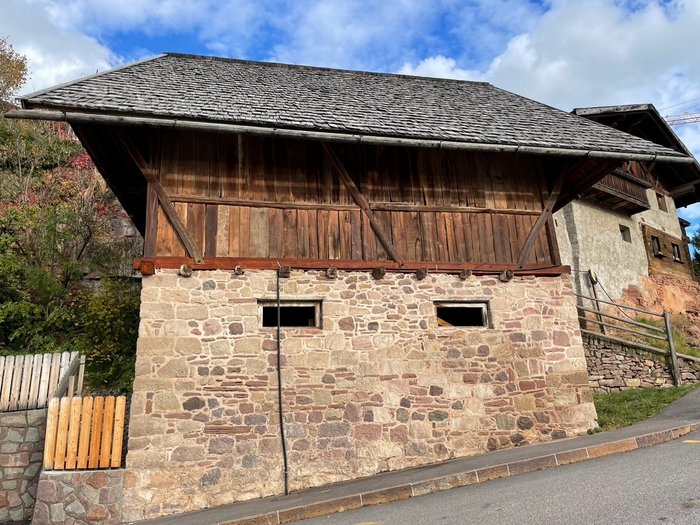 Nuovi percorsi per l’Alto Adige: La Piattaforma per il rurale continua a puntare sullo sviluppo sostenibile dei paesi Vecchio edificio con base in pietra e parte superiore in legno vicino a una strada
