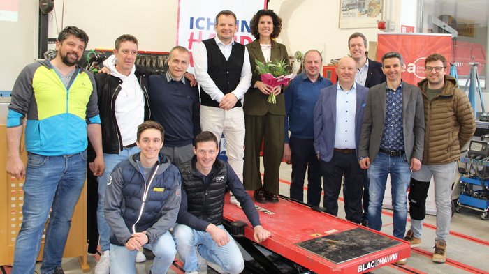 Gemeinsame Jahresversammlung stellt Digitalisierung und Zukunftsperspektiven in den Fokus Gruppenfoto von zwölf Personen in einer Werkstatt, eine Frau hält Blumen