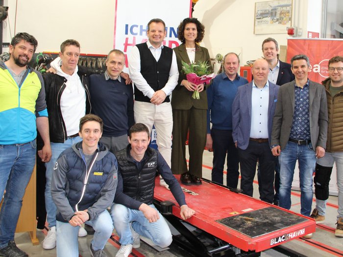 Assemblea annuale congiunta incentrata sulla digitalizzazione e sulle prospettive future Foto di gruppo di dodici persone in una officina, una donna tiene un mazzo di fiori