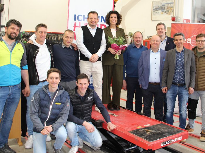 Gemeinsame Jahresversammlung stellt Digitalisierung und Zukunftsperspektiven in den Fokus Gruppenfoto von zwölf Personen in einer Werkstatt, eine Frau hält Blumen