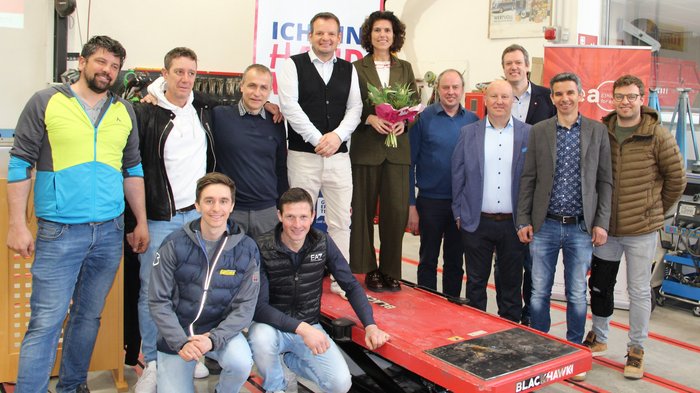 Assemblea annuale congiunta incentrata sulla digitalizzazione e sulle prospettive future Foto di gruppo di dodici persone in una officina, una donna tiene un mazzo di fiori