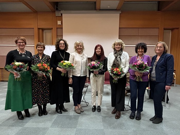 Le donne rafforzano la politica comunale Otto donne in una stanza, cinque tengono mazzi di fiori