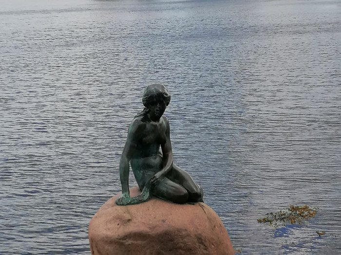 Reisefreudige Althandwerker/innen Bronzestatue der kleinen Meerjungfrau sitzt auf einem Felsen im Wasser