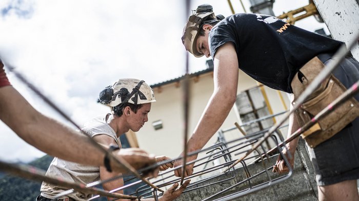 © Hannes Niederkofler Bauarbeiter arbeiten mit Metallbewehrung auf einer Baustelle im Freien