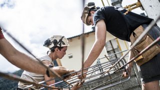 © Hannes Niederkofler Bauarbeiter arbeiten mit Metallbewehrung auf einer Baustelle im Freien