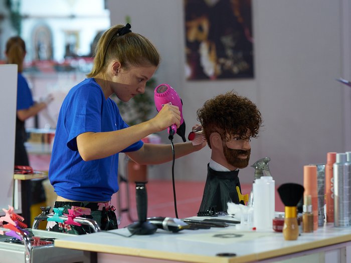 WorldSkills Italy: Lyon als Ziel Frau föhnt Haare an einer Friseur-Übungspuppe im Salon