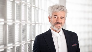 News Reifer Mann im Anzug vor einer Glaswand im Büro