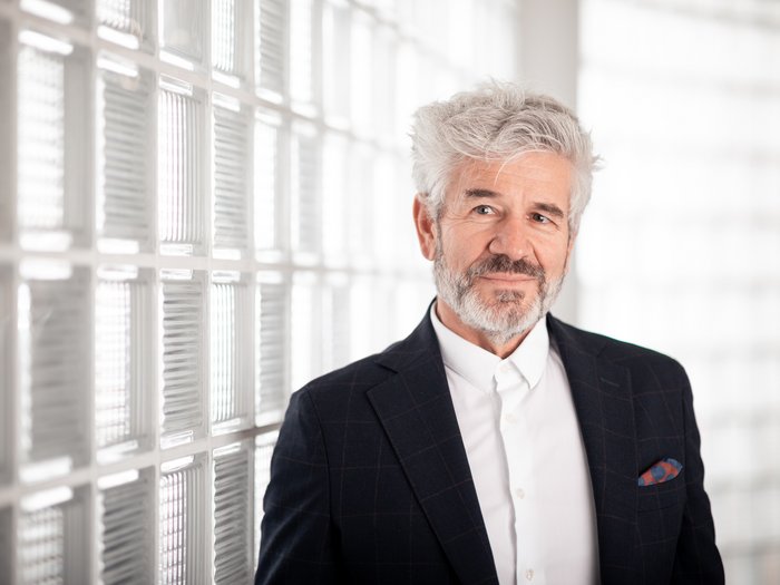 Richiesto un tavolo per l’edilizia Uomo maturo in abito davanti a una parete di vetro in ufficio