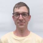 Waldarbeiter Porträt eines Mannes mit Brille und gelbem T-Shirt vor hellgrauem Hintergrund