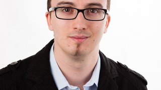 News Porträt eines jungen Mannes mit Brille und schwarzer Jacke vor weißem Hintergrund