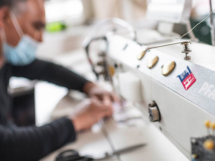 Covid-Lohnausgleichskasse: Auszahlungen über FSBA in den nächsten Tagen Mann mit Maske arbeitet an einer Nähmaschine in der Werkstatt