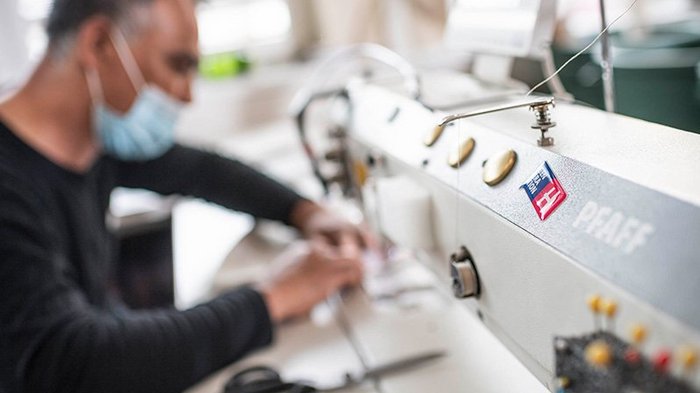 Covid-Lohnausgleichskasse: Auszahlungen über FSBA in den nächsten Tagen Mann mit Maske arbeitet an einer Nähmaschine in der Werkstatt