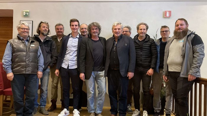 Maler/innen und Lackierer/innen: Neuer Obmann und Berufsbeirat Gruppe von elf Männern steht in einem Raum mit bemalter Wand