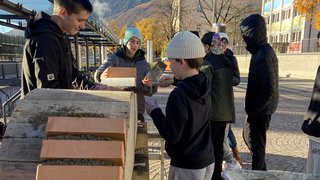 News Jugendliche mauern Ziegelsteine bei sonnigem Herbstwetter im Freien
