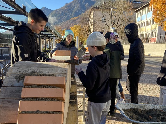 Einblicke in den Berufsalltag Jugendliche mauern Ziegelsteine bei sonnigem Herbstwetter im Freien